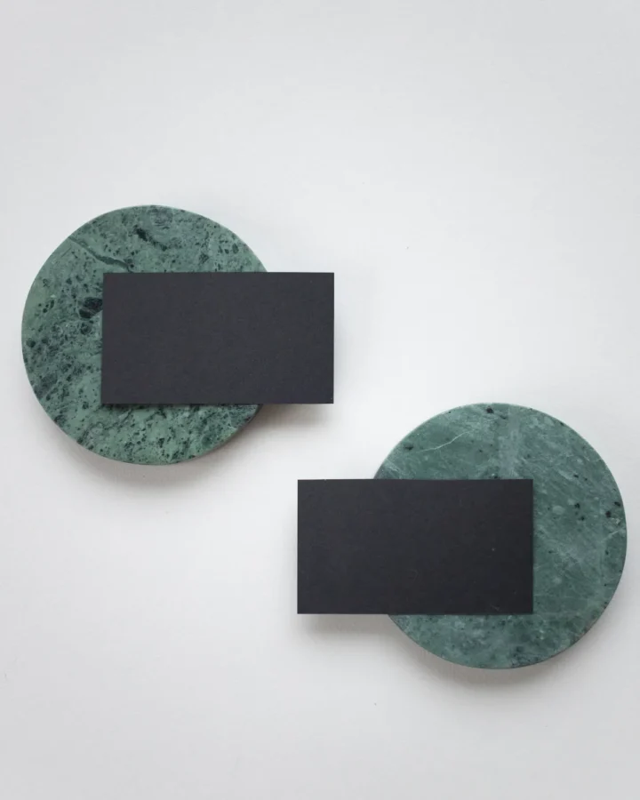 Black soft-touch business cards on green marble coasters
