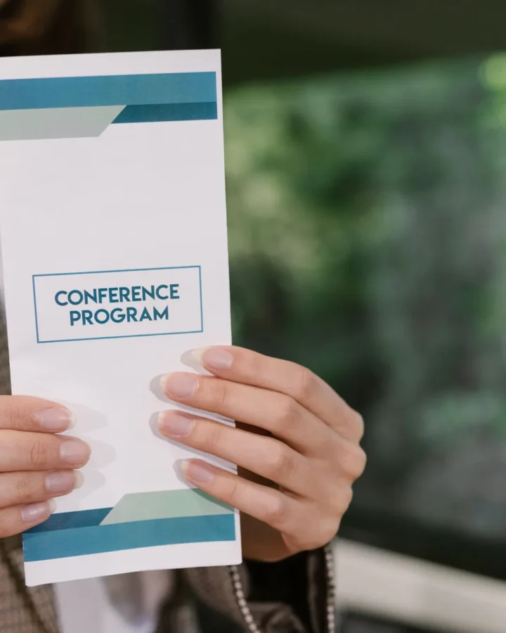 Hands holding a tri-fold conference programme
