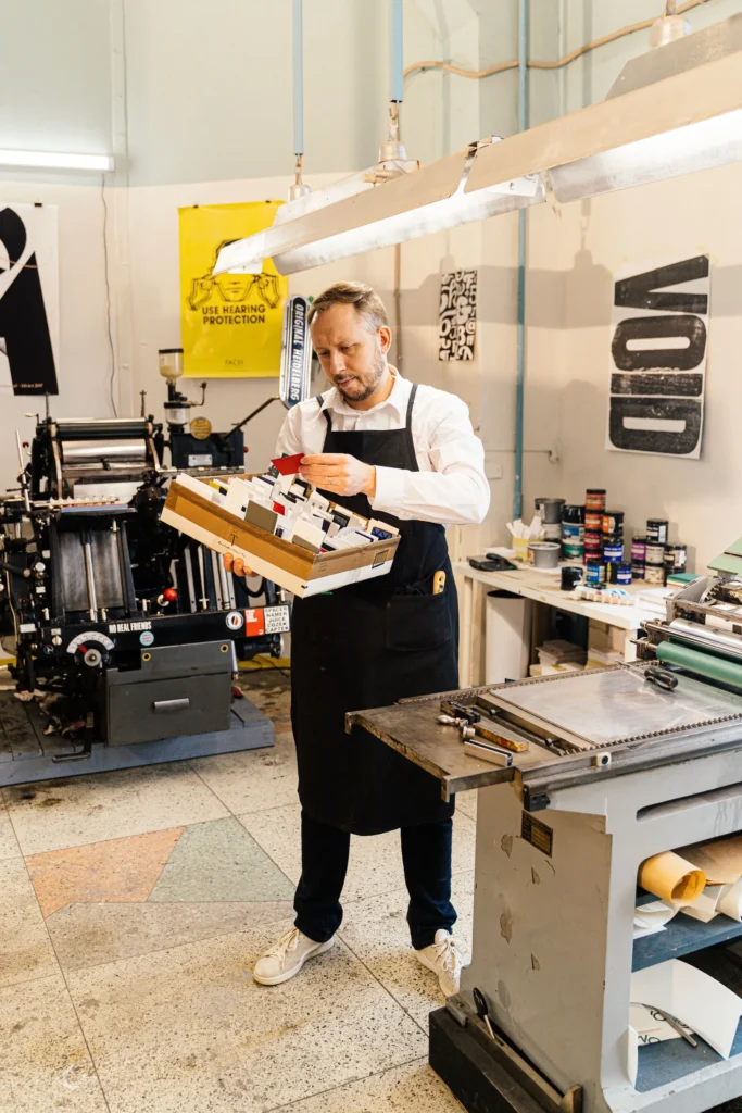 Printer in an apron working at a letterpress