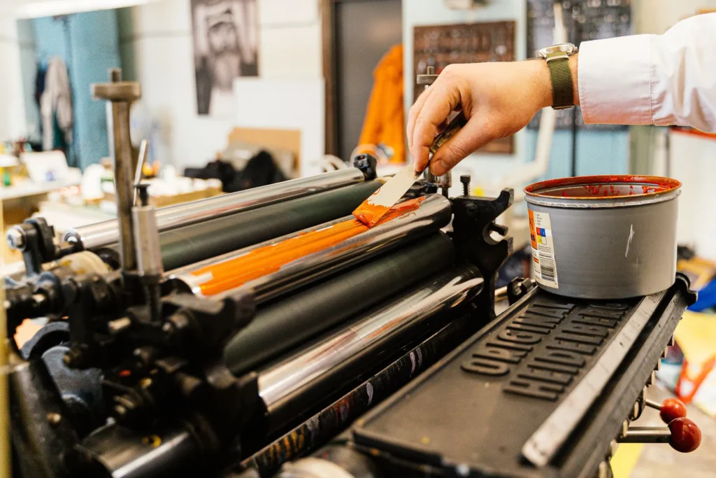 Hand spreading ink onto a press